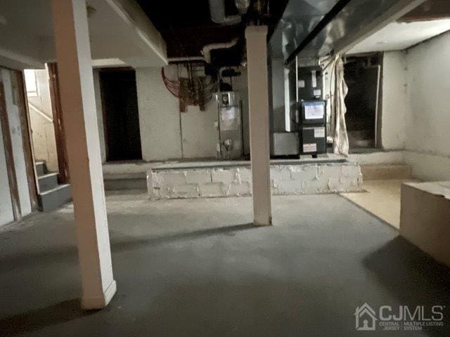 unfinished basement featuring stairs and water heater