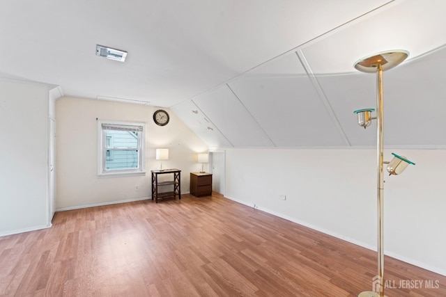 additional living space featuring wood finished floors, vaulted ceiling, and baseboards