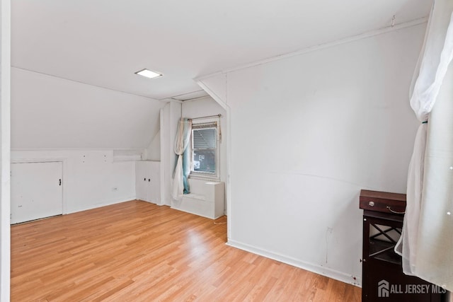 bonus room featuring lofted ceiling, light wood-style flooring, and baseboards