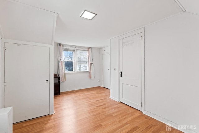unfurnished bedroom with light wood finished floors and vaulted ceiling