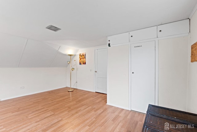 additional living space with light wood-style floors, baseboards, and lofted ceiling