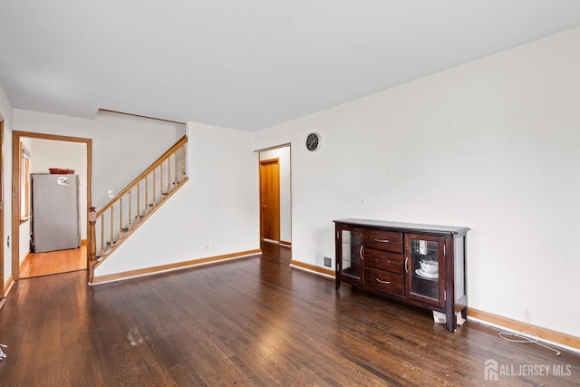 unfurnished living room with baseboards, stairway, wood finished floors, and visible vents
