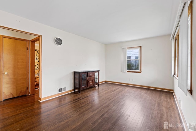 unfurnished living room with baseboards, visible vents, and wood finished floors