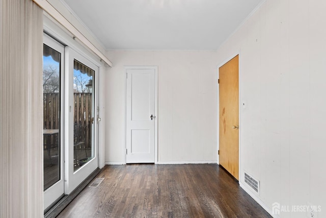 spare room with wood finished floors, crown molding, and baseboards