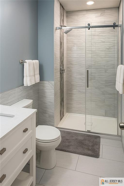 344 Danbury Ln Unit 344, East Brunswick, NJ 08816 - bathroom featuring tile patterned floors, a shower stall, vanity, and tile walls