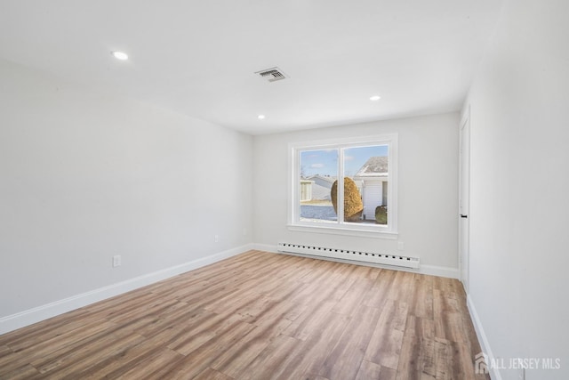 empty room with light hardwood / wood-style flooring and a baseboard heating unit