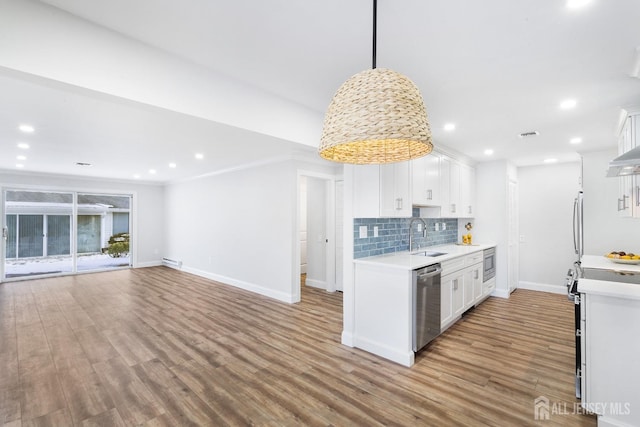 kitchen featuring white cabinetry, sink, tasteful backsplash, decorative light fixtures, and appliances with stainless steel finishes