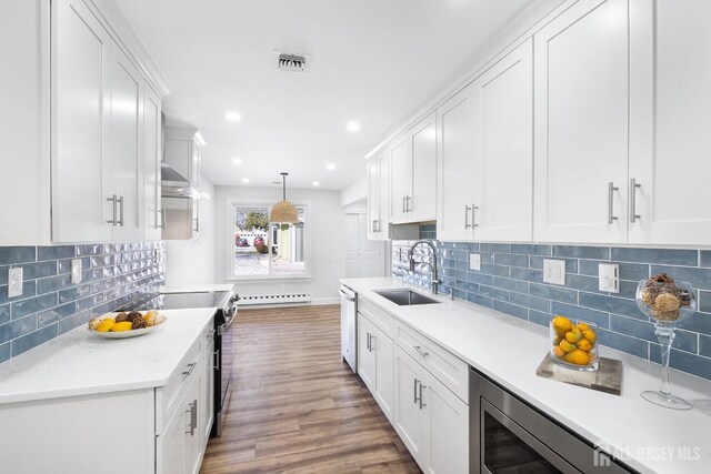 kitchen with dark hardwood / wood-style flooring, stainless steel appliances, sink, decorative light fixtures, and white cabinets