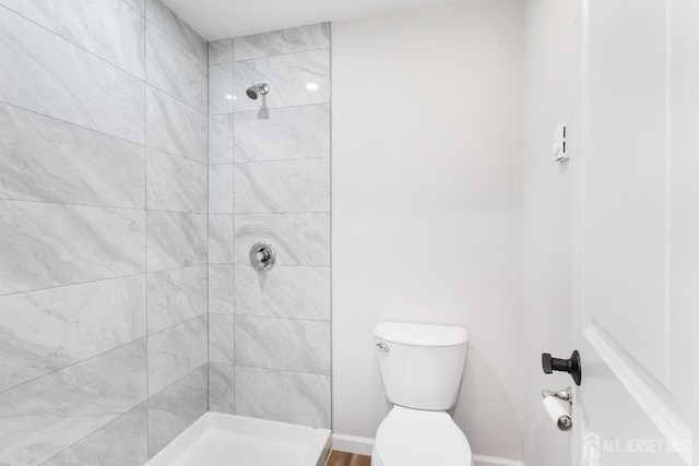 bathroom featuring a tile shower and toilet