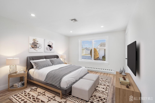 bedroom featuring hardwood / wood-style floors and a baseboard heating unit