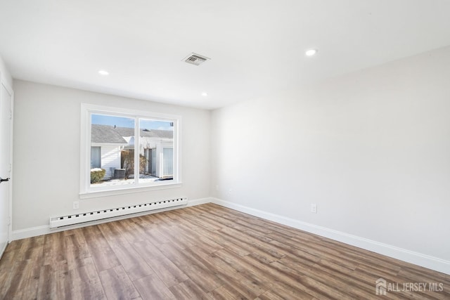 spare room featuring wood-type flooring and a baseboard radiator