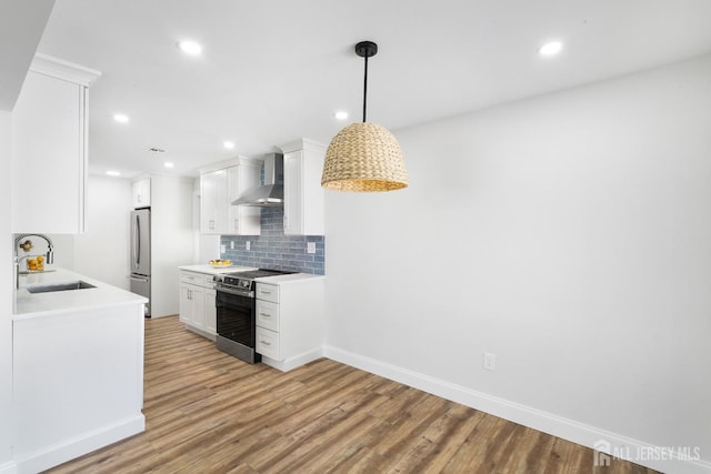 kitchen with hanging light fixtures, sink, wall chimney exhaust hood, appliances with stainless steel finishes, and white cabinetry