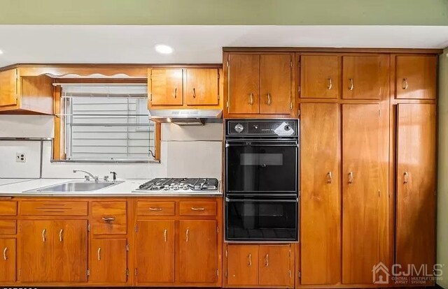 kitchen featuring sink, black double oven, and stainless steel gas cooktop