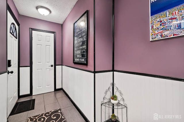 19 Lake Ave Unit 6A, East Brunswick, NJ 08816 - doorway featuring a textured ceiling, wainscoting, and light tile patterned flooring