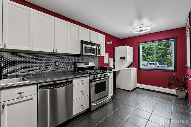 19 Lake Ave Unit 6A, East Brunswick, NJ 08816 - kitchen with appliances with stainless steel finishes, stacked washer / drying machine, dark tile patterned floors, dark countertops, and white cabinetry