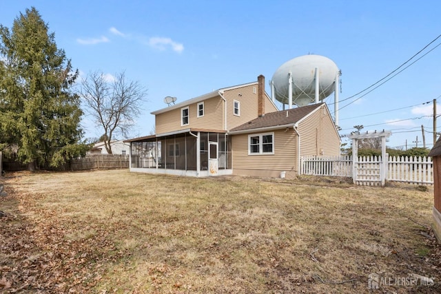 back of property with a fenced backyard, a chimney, a sunroom, and a lawn