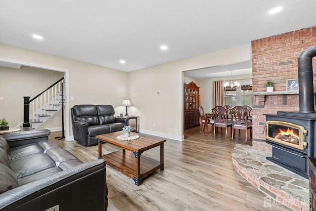 living room featuring baseboards, recessed lighting, stairway, light wood-style flooring, and a wood stove