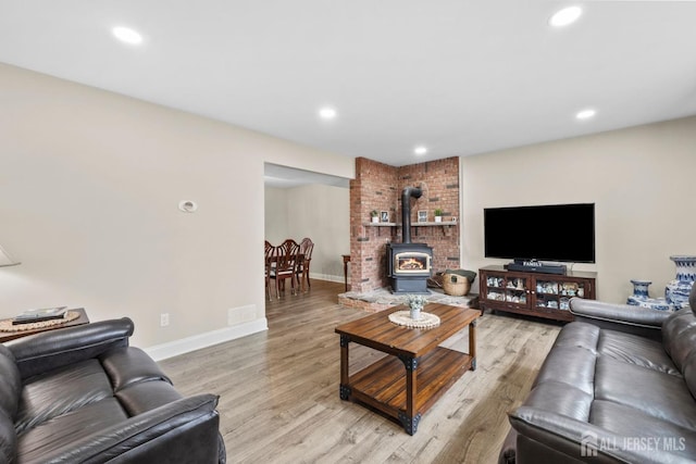living room with a wood stove, light wood-type flooring, recessed lighting, and baseboards