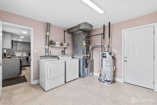 washroom featuring washer and dryer, laundry area, baseboards, and water heater