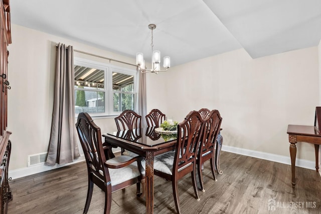 dining space featuring baseboards, a chandelier, and wood finished floors