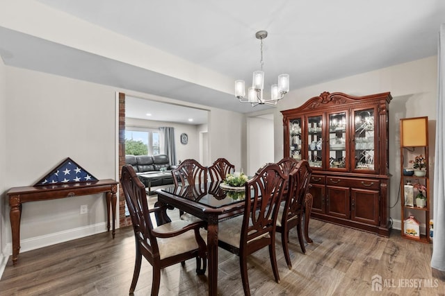 dining space with wood finished floors, an inviting chandelier, and baseboards
