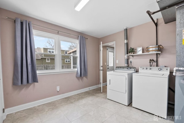 laundry area featuring baseboards, light tile patterned floors, washer and clothes dryer, and laundry area