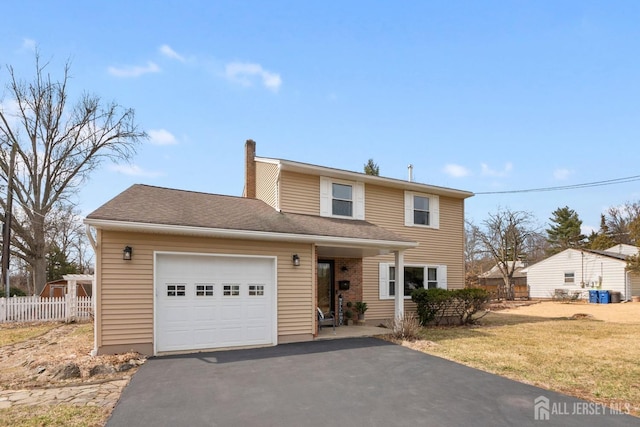 traditional-style home featuring a garage, a front yard, fence, a chimney, and driveway