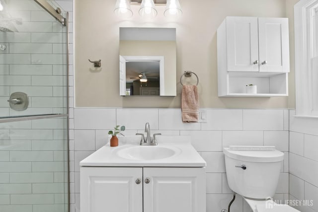 bathroom featuring tiled shower, vanity, tile walls, and toilet
