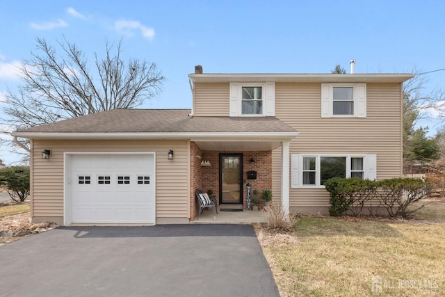 traditional-style house featuring a front yard, an attached garage, a chimney, aphalt driveway, and brick siding
