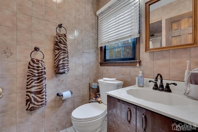 bathroom with vanity, toilet, and tile walls