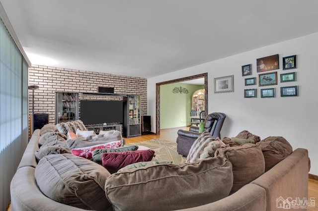 living room featuring brick wall, light hardwood / wood-style flooring, and a fireplace