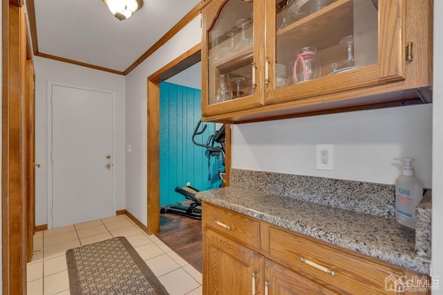 kitchen with crown molding, light wood-type flooring, and light stone counters