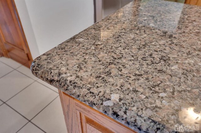 interior details with tile patterned flooring and stone counters