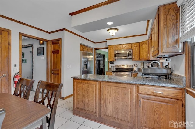 kitchen featuring dark stone countertops, light tile patterned floors, crown molding, and stainless steel appliances