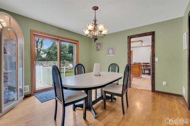 dining space with light hardwood / wood-style floors and a chandelier