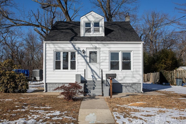 view of front of home with entry steps, a shingled roof, a chimney, and fence