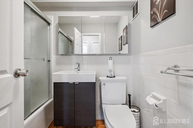 150 Overlook Ave Unit 15E, Hackensack, NJ 07601 - bathroom with combined bath / shower with glass door, tile walls, vanity, and wainscoting