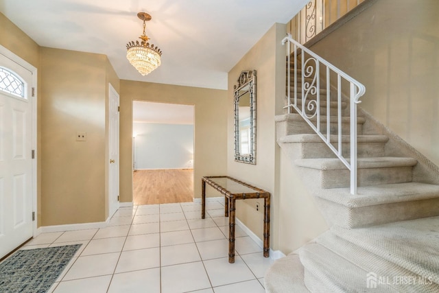 entryway featuring an inviting chandelier, stairway, light tile patterned floors, and baseboards