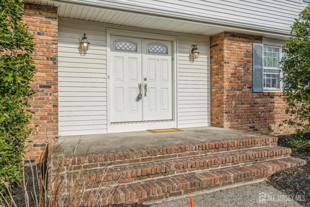 doorway to property featuring brick siding and a porch