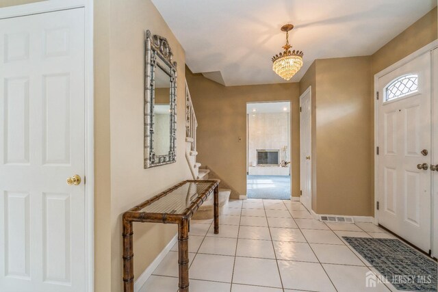 foyer entrance with light tile patterned floors and an inviting chandelier