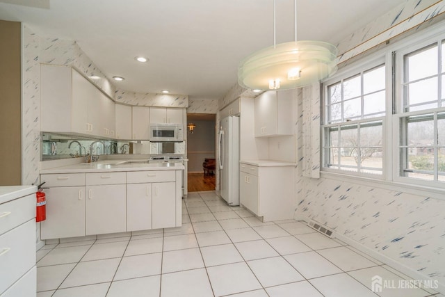 kitchen with white cabinetry, sink, white appliances, and pendant lighting