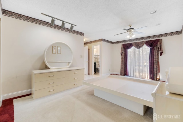 carpeted bedroom featuring ceiling fan, rail lighting, a textured ceiling, and baseboards