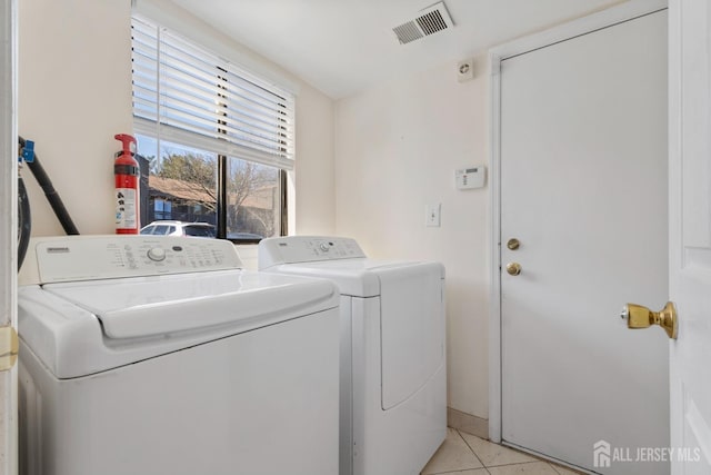 clothes washing area featuring washing machine and clothes dryer, laundry area, visible vents, and light tile patterned floors