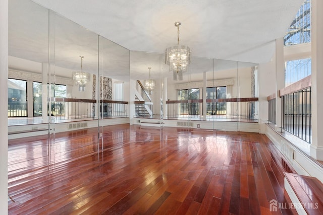 spare room with stairway, wood-type flooring, and a chandelier