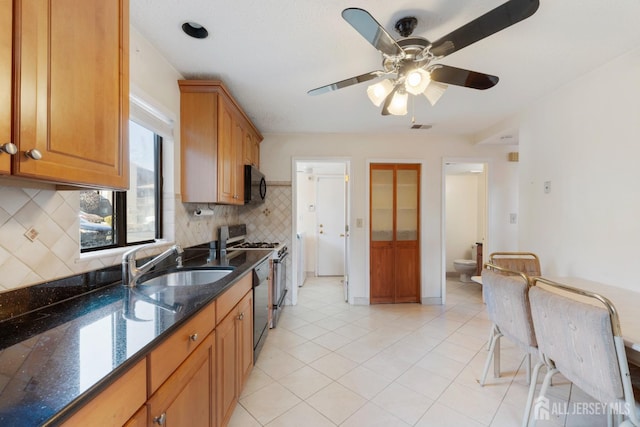 kitchen featuring visible vents, black appliances, a sink, tasteful backsplash, and dark stone counters