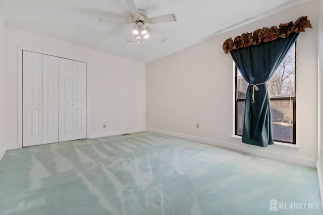 unfurnished bedroom featuring baseboards, carpet floors, a closet, and ceiling fan