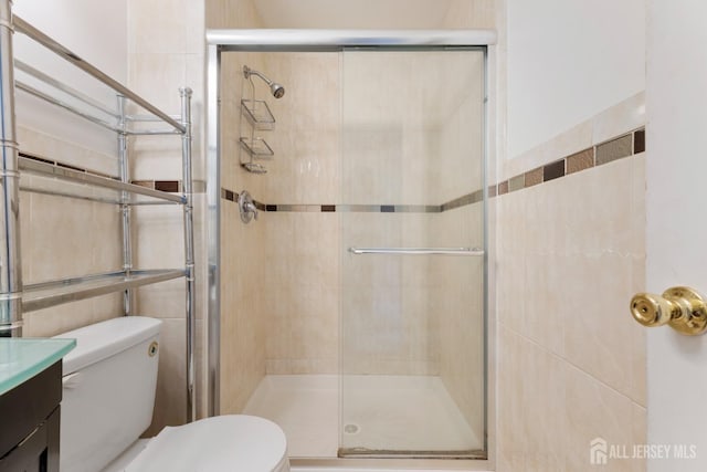 full bathroom with tile walls, a shower stall, toilet, and vanity