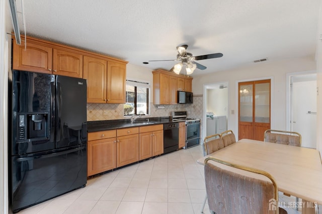 kitchen featuring visible vents, black appliances, a sink, tasteful backsplash, and dark countertops