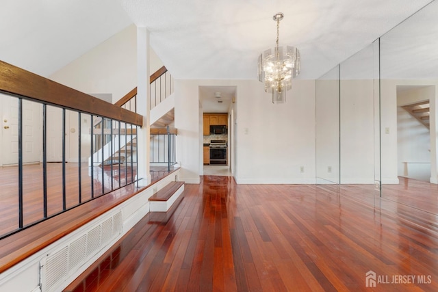 interior space featuring hardwood / wood-style floors, a notable chandelier, and baseboards