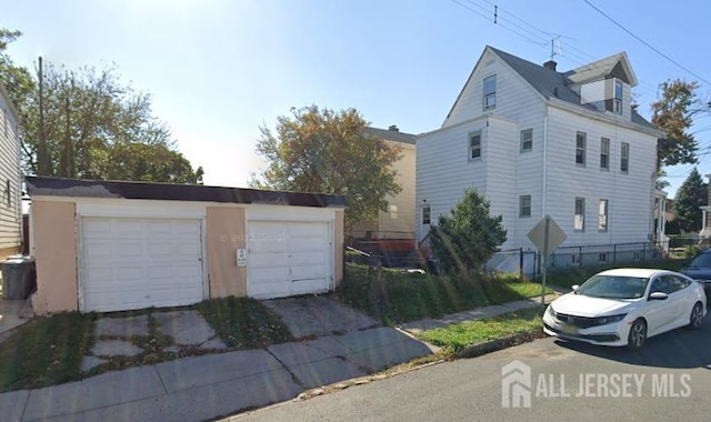 view of property exterior with an outbuilding, fence, and a detached garage